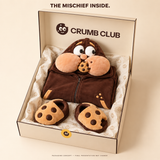 Packaging concept: a folded Goinfre onesie and separate cookie slippers in a Crumb Club box. Final presentation may change.